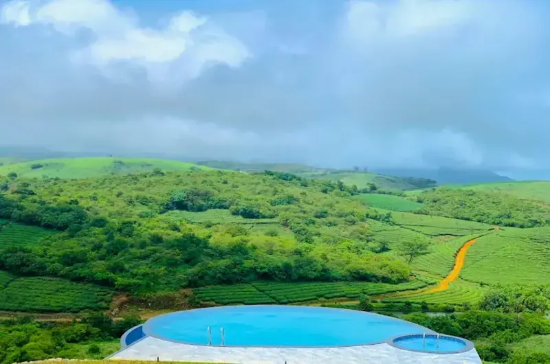 Outdoor swimming pool with scenic mountain and cloud views at Orange Valley Hills Resort Vagamon