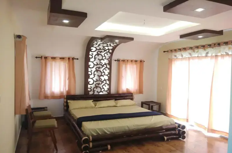 Cozy resort bedroom interior featuring a double bed and warm decorative wall accents at Vagamon Bamboo Nest Resort
