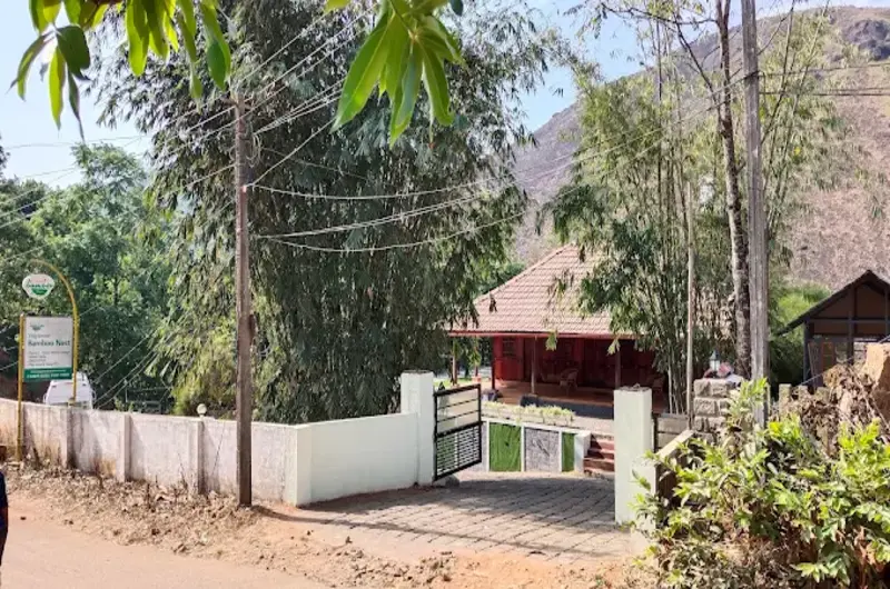 Entrance surrounded by tropical trees and palm foliage leading to Vagamon Bamboo Nest Resort