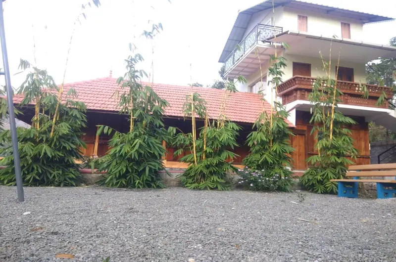 Exterior view of the multi-story Vagamon Bamboo Nest Resort building with paved courtyard and lush greenery