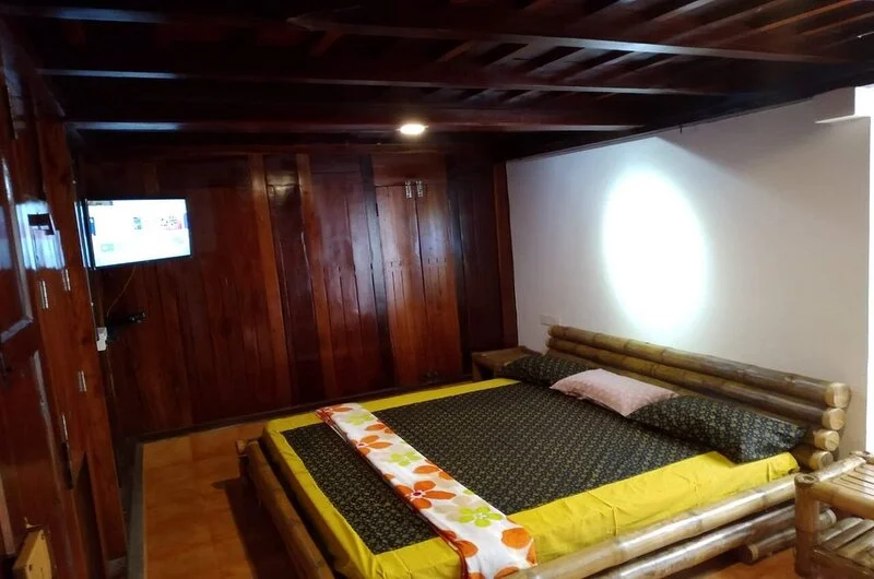 Warm wooden cottage bedroom with plush double bed and soft ambient lighting at Vagamon Bamboo Nest Resort