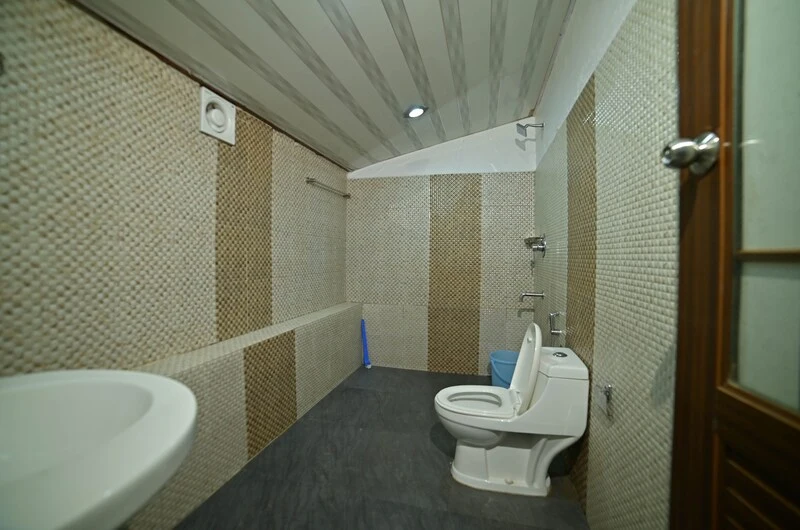 Clean modern attached bathroom with tiled walls and sanitary fittings at Wood Castle Residency