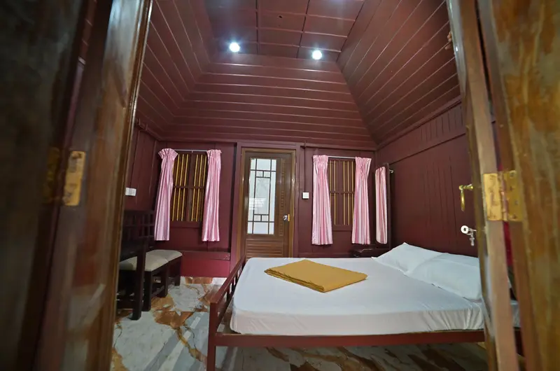 Rustic wooden cottage bedroom with sloped ceiling and double bed at Wood Castle Residency Vagamon
