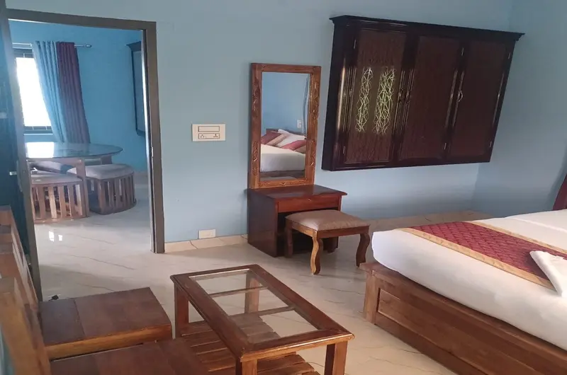 Cozy resort guest bedroom featuring wooden furniture and seating area at Wood Castle Residency