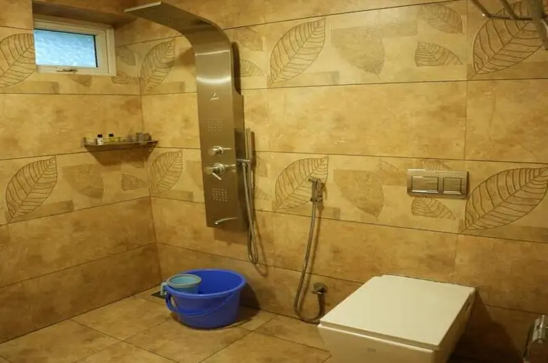 Clean attached bathroom with stone texture tiles and modern sanitary fittings at Vaga Mist Resort
