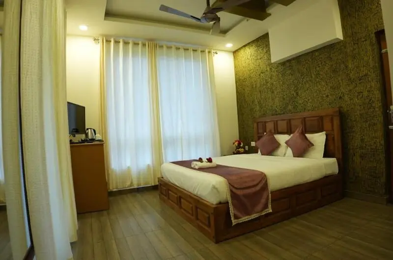 Cozy hotel guest room featuring ambient wall lighting and plush bedding in Vagamon