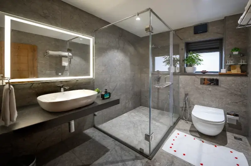 Modern attached bathroom featuring glass shower enclosure, LED vanity mirror, and sleek counter basin