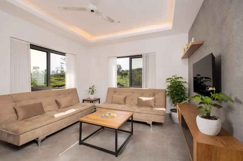 Deluxe suite sitting room featuring plush L-shaped sofa, wooden coffee table, and indoor plants
