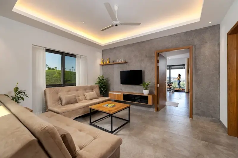 Spacious living room suite featuring modern couch seating, tray ceiling lighting, and large windows
