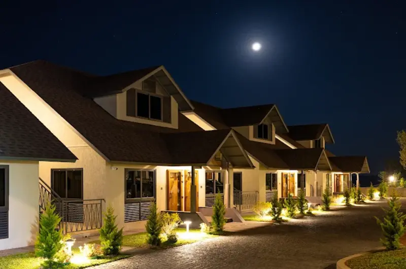 Night view of cottage villa facade illuminated under full moon night sky at Elysian Vale Resort