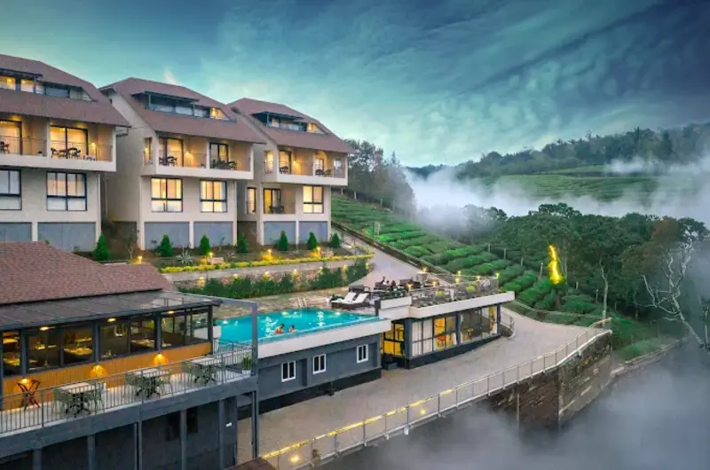 Exterior view of modern multi-story building and illuminated outdoor pool deck at Elysian Vale Resort Vagamon