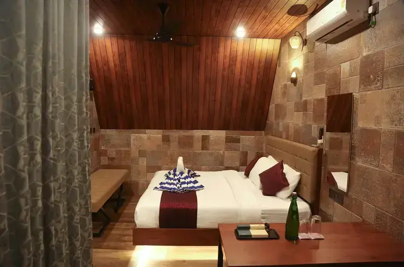 Cozy wooden cottage bedroom featuring double bed, ambient wall lights, and air conditioner