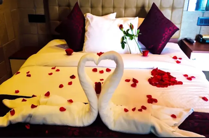 Honeymoon bed decoration with towel swan art, rose petals, and colorful cushions at Cloud Cabana Holidays