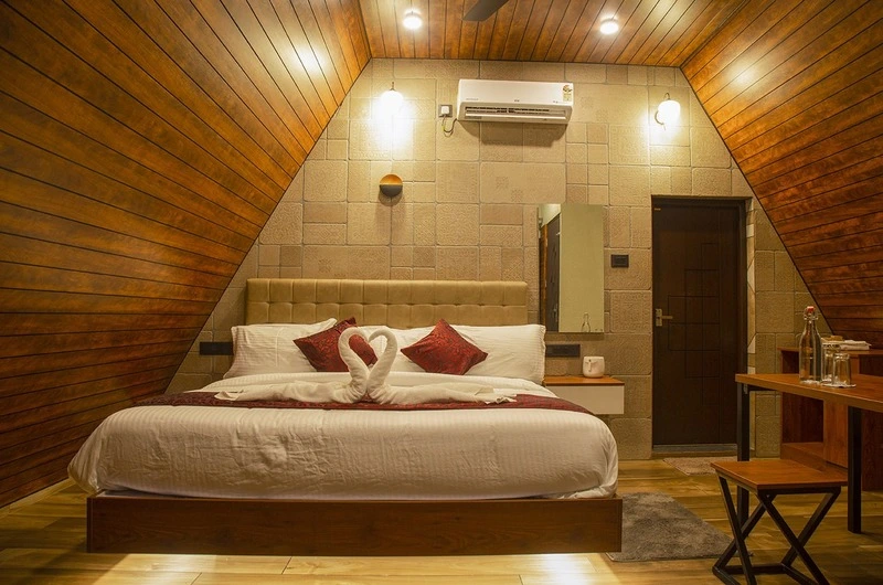 Cozy wooden villa guest room featuring double bed setup and warm timber paneling in Vagamon