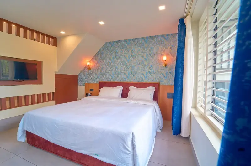 Bright deluxe bedroom interior with wood accent walls at Choice Holidays Resort Vagamon.