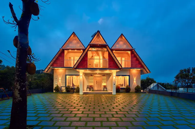 Illuminated front exterior of a luxury three-gabled villa at Choice Holidays Resort Vagamon.