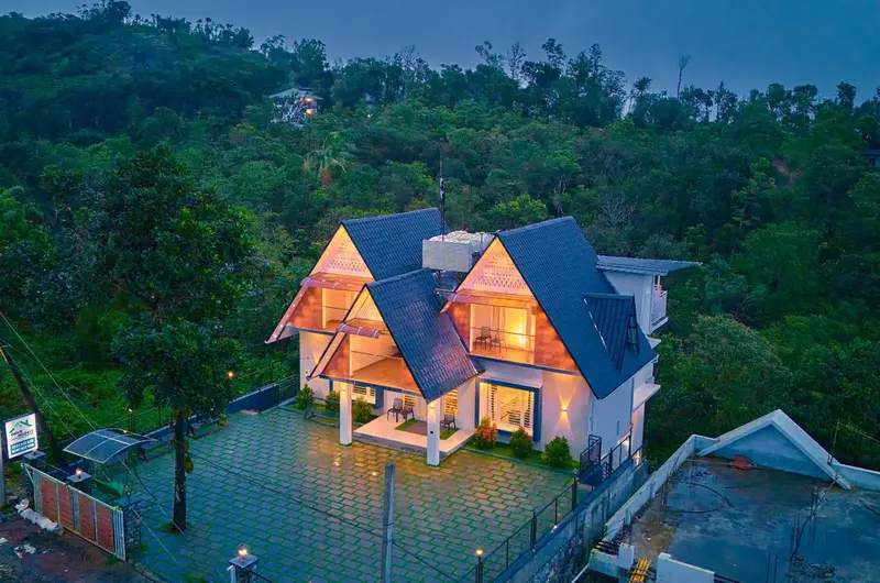 Choice Holidays Resort Vagamon premium cottage exterior surrounded by trees at night.
