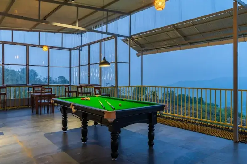Outdoor recreation deck with a billiards pool table at The Hosteller Bam Vagamon during twilight.