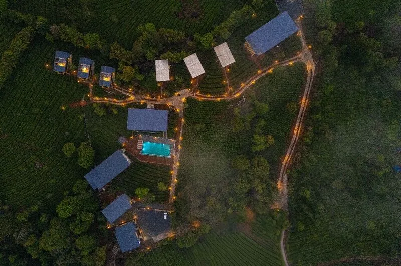 Aerial view of The Hosteller Bam Vagamon cabins and swimming pool surrounded by lush greenery.