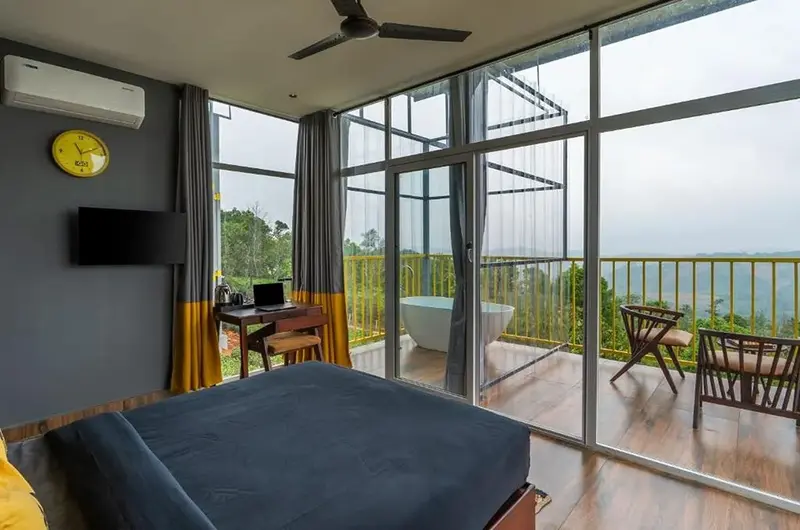 Luxury glass-front bedroom with private balcony view at The Hosteller Bam Vagamon.