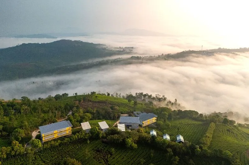 Scenic morning view of The Hosteller Bam Vagamon overlooking misty mountain hills and clouds.