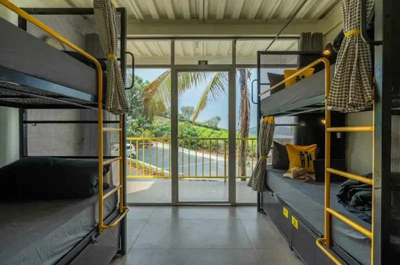 Modern bunk bed dorm layout with a scenic balcony view at The Hosteller Bam Vagamon.