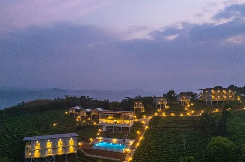 Illuminated mountain cabins at The Hosteller Bam Vagamon resort exterior at twilight.