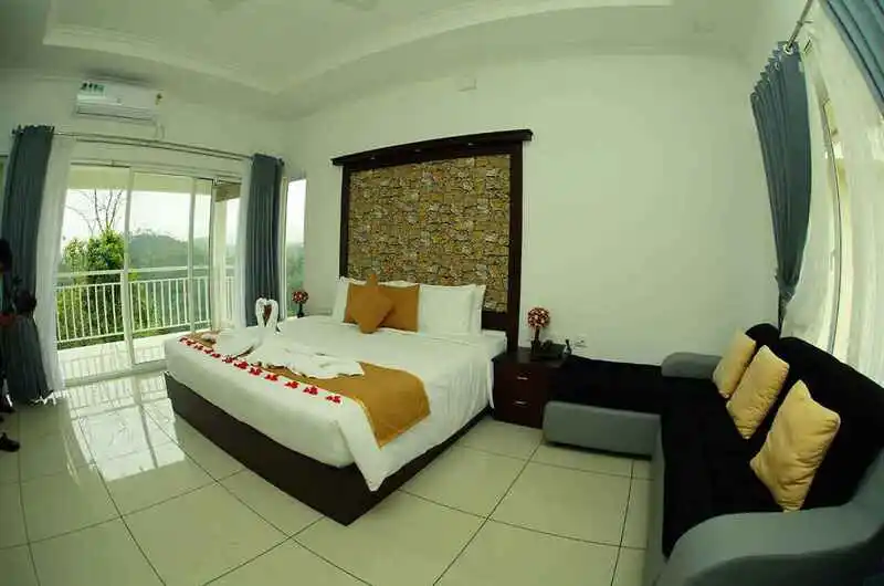Deluxe double bedroom with contemporary wood accent walls and scenic window at The Grasmere Resort Vagamon.