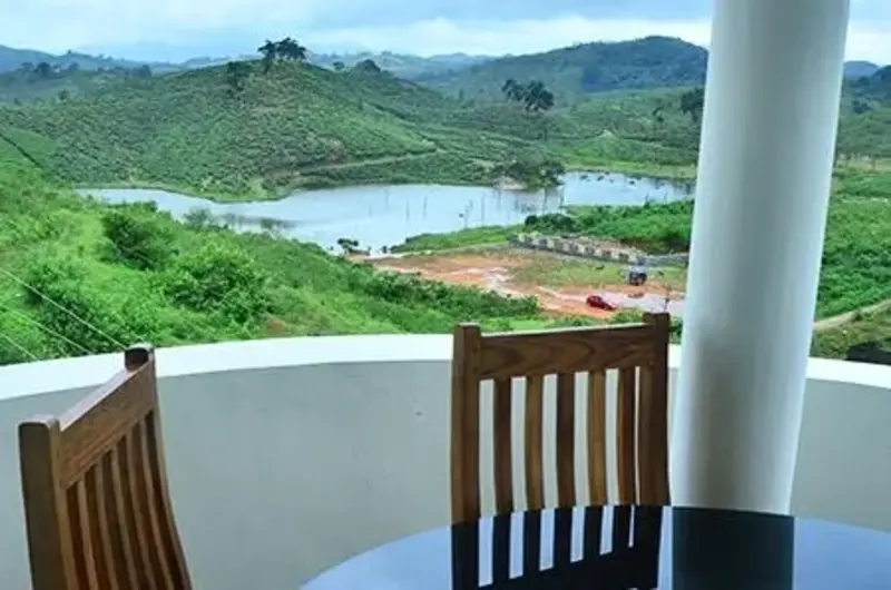 Private room balcony seating with wooden chairs overlooking lush green hills in Vagamon at Dew Drops Holidays