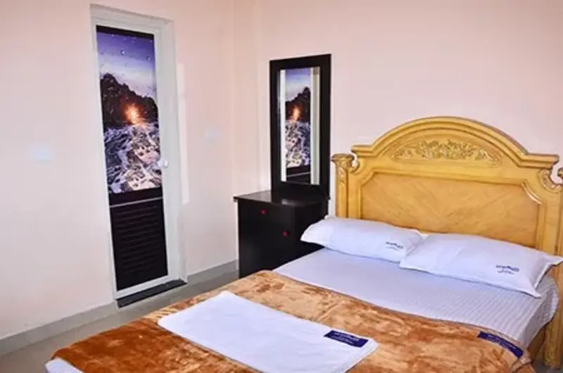 Deluxe guest bedroom featuring a spacious double bed with carved wooden headboard and modern lighting