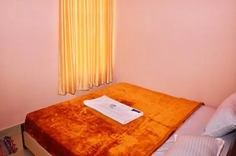 Comfortable hotel guest bedroom suite with bright orange bedding accent and warm ambient lighting