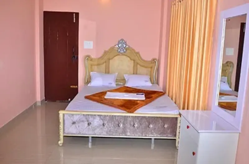 Modern deluxe guest room with plush double bed, tiled flooring, and elegant wall sconce lighting