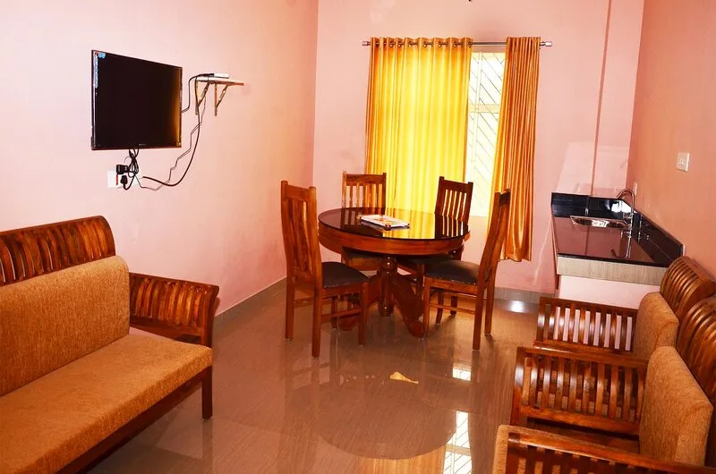 Cozy hotel suite living lounge with plush orange sofas, glass coffee table, and warm curtained windows