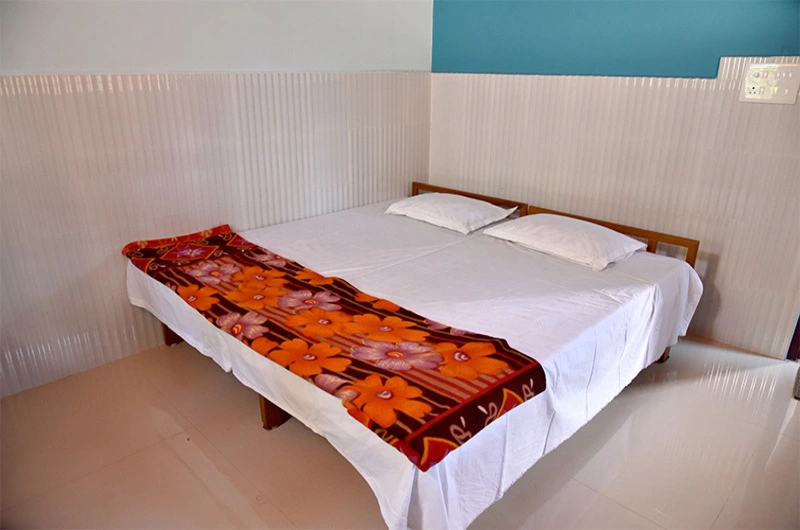 Cozy guest bedroom suite featuring a double bed with floral accent blanket at Padmalayam Homestay