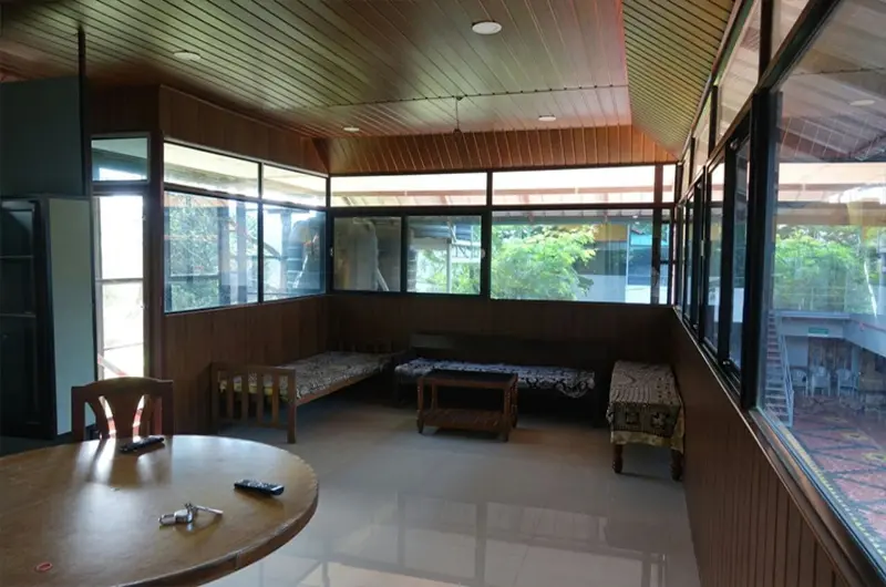Spacious homestay living room lounge with comfortable wooden seating and warm interior decor