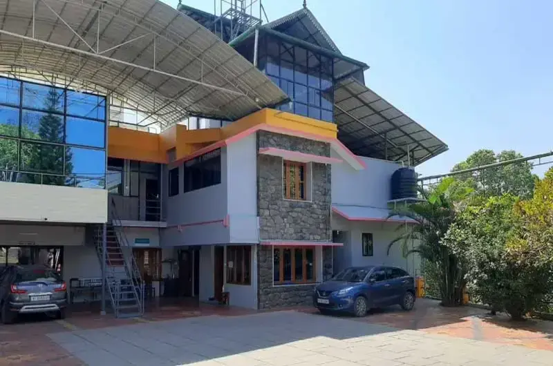 Front view of Padmalayam Homestay featuring glass windows, balcony, and paved driveway parking
