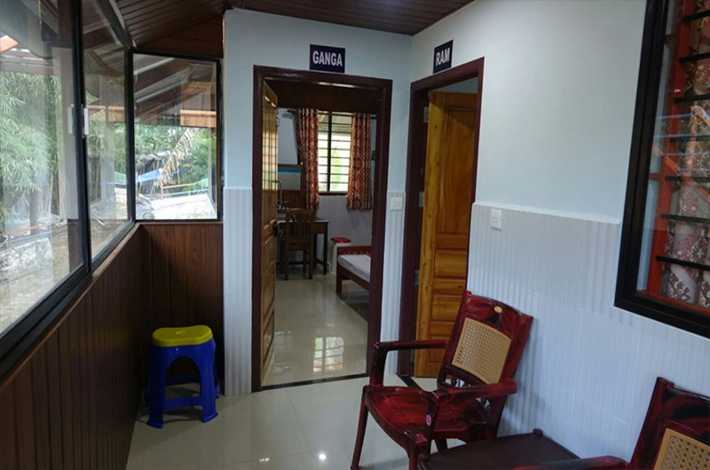 Cozy indoor hallway balcony with wooden chairs and window views at Padmalayam Homestay