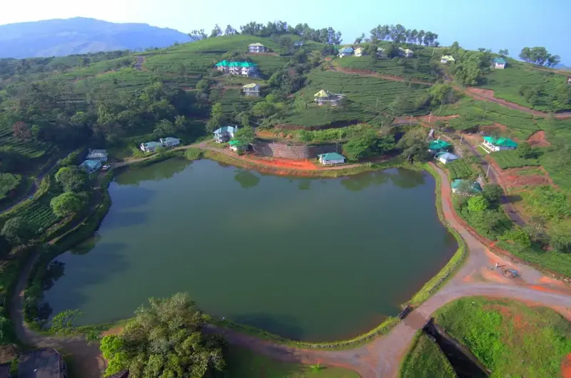 Aerial view of natural lake pond surrounded by lush green foliage and soil pathways at Orion County Vagamon