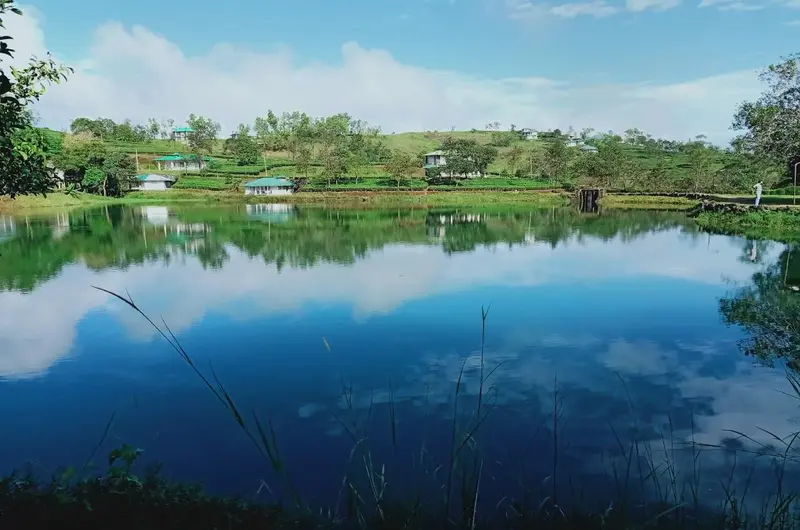 Serene view of a natural lake pond reflecting blue skies and green trees at Orion County Vagamon