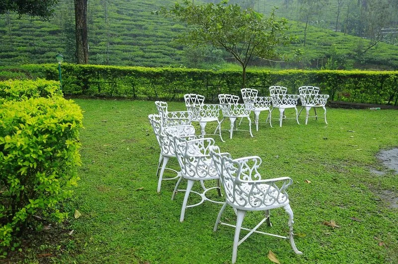 White wrought-iron patio seating arranged on a manicured garden lawn overlooking tea gardens