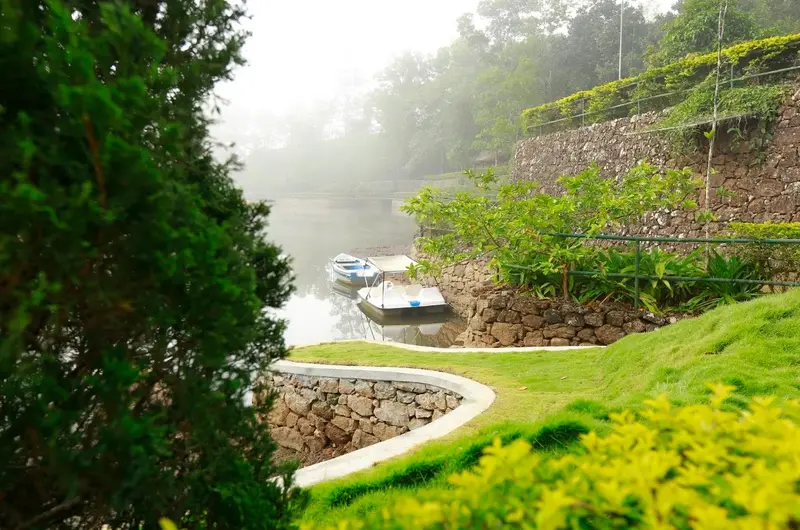 Serene natural lake pond reflecting green tea garden hills at SAJ Vagamon Hideout