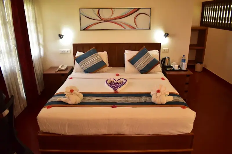Decorated guest bedroom featuring a king-size bed with towel swan art, patterned accent wall, and ambient lighting