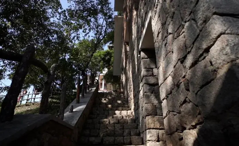 Resort room veranda deck with stone boundary wall overlooking forest trees at Adrak Summer Sand Hill Resort