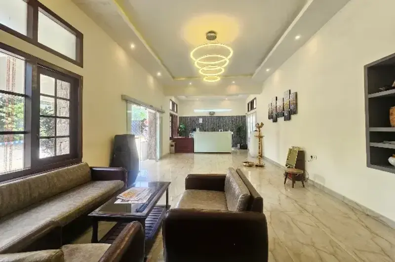 Modern resort reception lobby with plush lounge seating, chandelier lighting, and large glass windows at Adrak Summer Sand Hill Resort