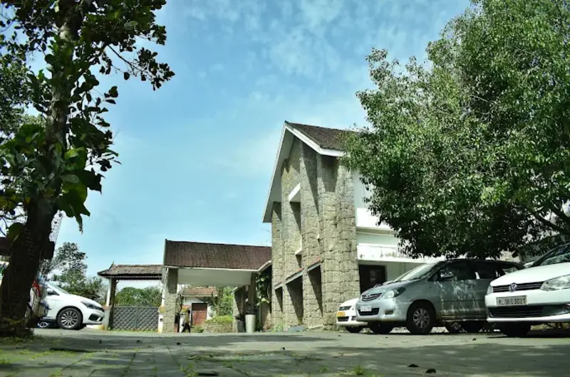 Exterior view of resort building with stone wall architecture and guest parking at Adrak Summer Sand Hill Resort Vagamon