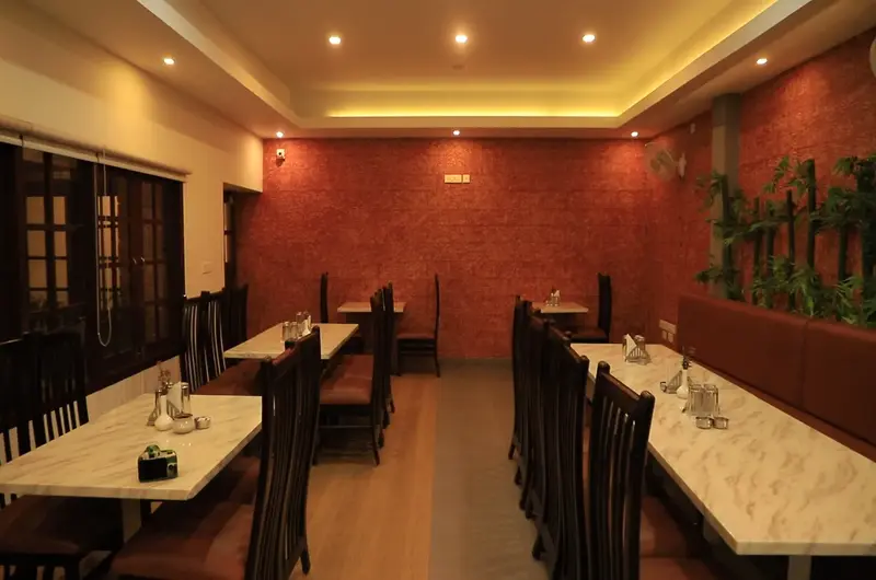 Bright resort dining hall featuring tray ceiling ambient lights and long dining tables at Adrak Summer Sand Hill Resort