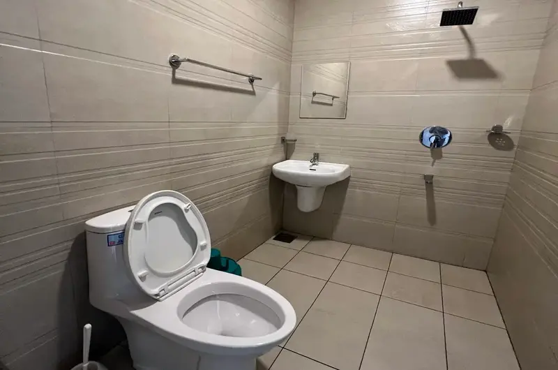 Clean attached guest bathroom featuring modern toilet, sink, and wall shower fixtures