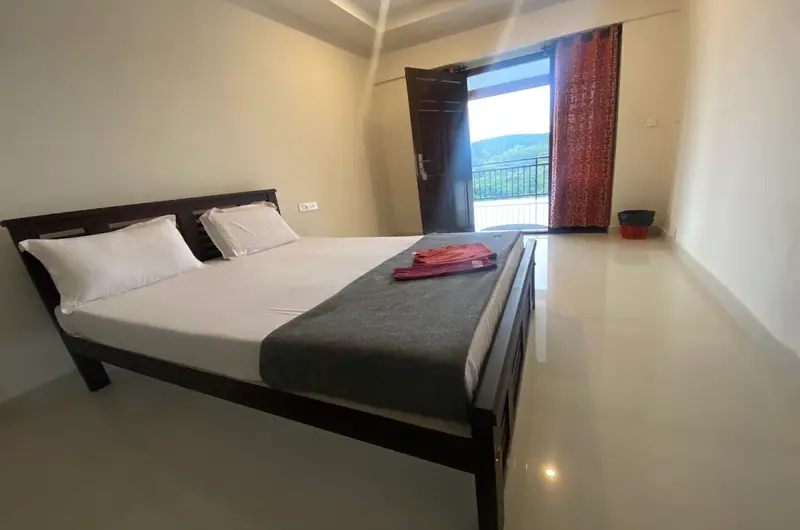 Cozy guest room bedroom featuring a comfortable double bed with red throw blanket and window view