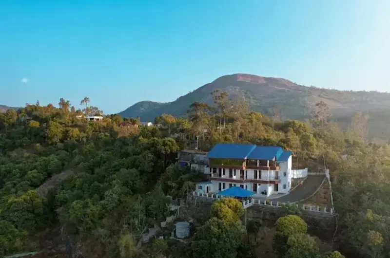 Aerial view of Moon Palace Kuttikanam building surrounded by lush green hills