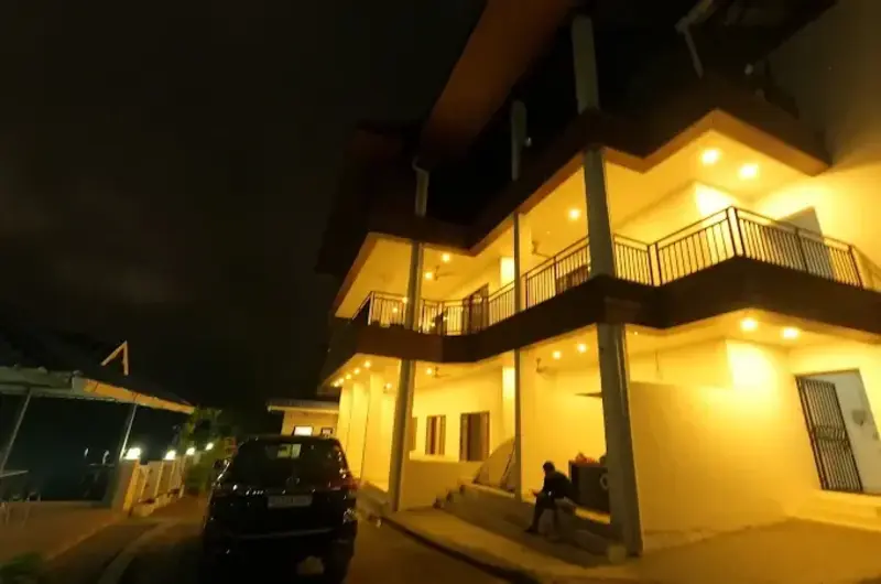 Warmly lit multi-story homestay building exterior at night at Moon Palace Kuttikanam